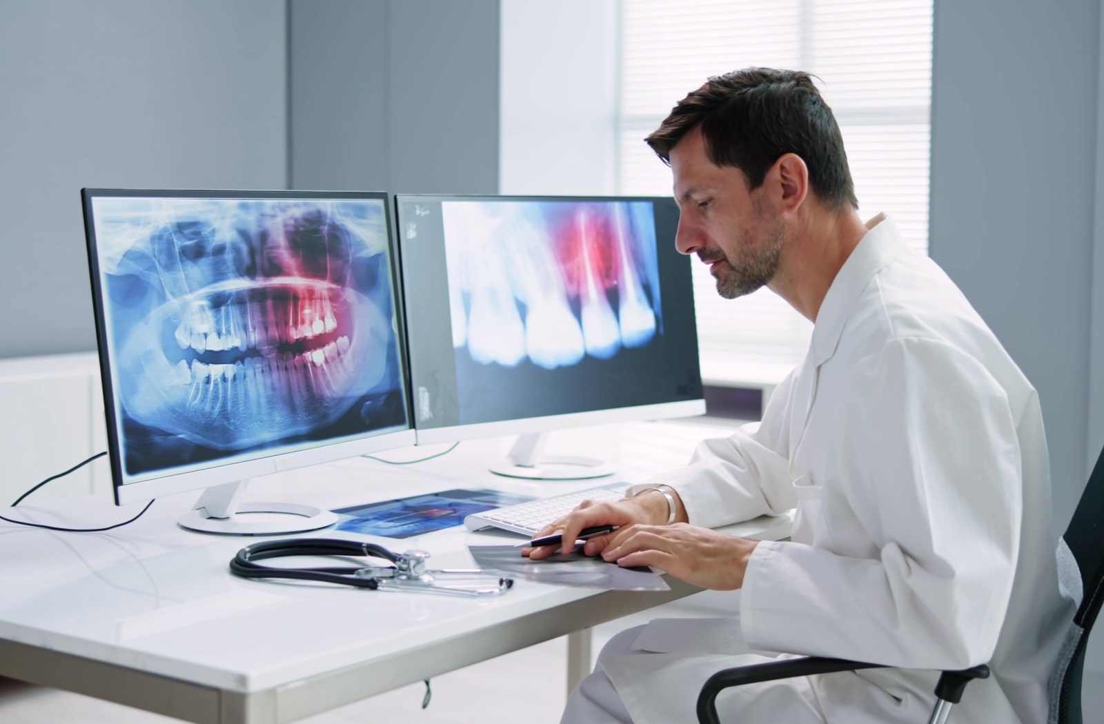A dentist reviews their patient's digital X-rays on their computer.